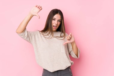 Kafkasyalı genç bir kadın soyutlanmış poz veriyor başparmağını aşağı gösteriyor ve hoşlanmadığını ifade ediyor..