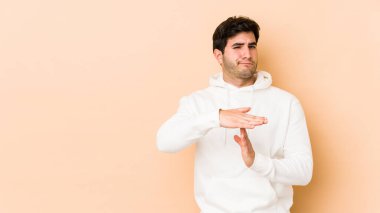 Bej arka planda izole edilmiş genç bir adam bir mola hareketi gösteriyor..