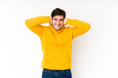 Genç adam beyaz arka planda izole edilmiş. Kulakları elleriyle kapatıyor. Gürültülü sesler duymamaya çalışıyor..