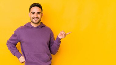Sarı fırında izole edilmiş genç beyaz bir adam işaret parmağıyla işaret ederek gülümsüyor..
