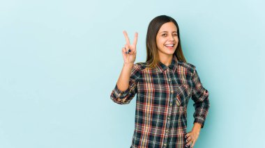 Mavi arka planda izole edilmiş genç bir kadın iki numarayı parmaklarıyla gösteriyor..