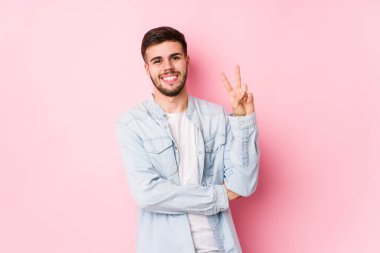 Beyaz arka planda poz veren Kafkasyalı genç iş adamı iki numarayı parmaklarıyla gösteriyor..