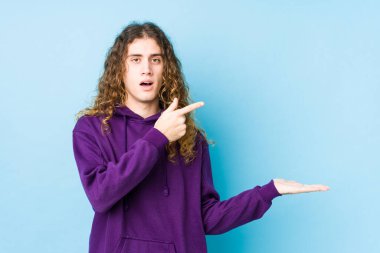 Uzun saçlı adam yalnız poz veriyor. Heyecanlı. Elinde bir kopyası var..