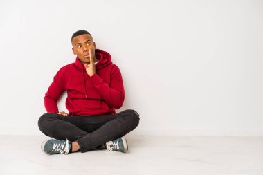 Yerde tek başına oturan genç latin adam gizli bir sıcak fren haberi veriyor ve yan bakıyor.