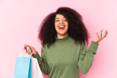 Genç afro kadın alışverişte soyutlanmış genç afro kadın yalnız başına bir gül tutan yalnız bir afro kadın hoş bir sürprizle karşılanıyor, heyecanlı ve el kaldırıyor.