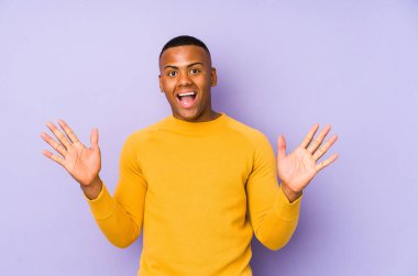 Mor arka plandaki genç latin adam zaferi ya da başarıyı kutluyor, şaşırmış ve şok olmuş..