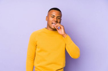 Mor arka planda izole olmuş, tırnak yiyen, gergin ve endişeli genç bir Latin..