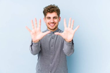 Sarışın, kıvırcık saçlı, beyaz tenli bir adam 10 numarayı elleriyle gösteriyor..