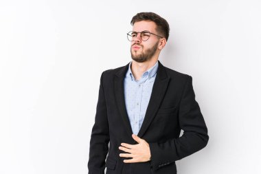 Beyaz arka planda poz veren beyaz tenli genç beyaz iş adamı genç beyaz iş adamı karnına dokunuyor, hafifçe gülümsüyor, yemek yiyor ve tatmin oluyor..