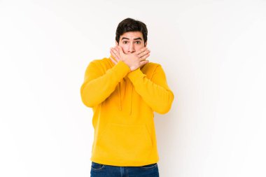 Beyaz arka planda izole edilmiş genç adam elleriyle ağzını kapatırken şok oldu..