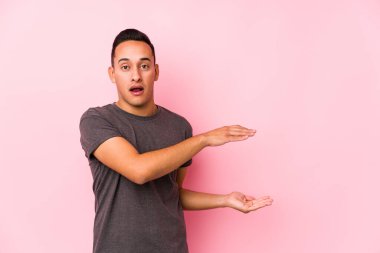 Pembe arka planda poz veren yog latin adam elleri arasında bir fotokopi alanı tutuyor..