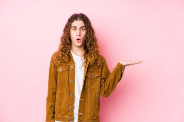 Genç, uzun saçlı, yalnız poz veren adam, avuç içi fotokopi alanı tutmaktan etkilenmiş..