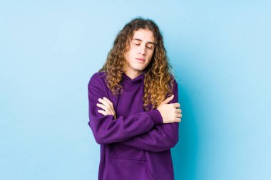 Uzun saçlı adam yalıtılmış sarılmalar sergiliyor, kaygısız ve mutlu gülümsüyor..