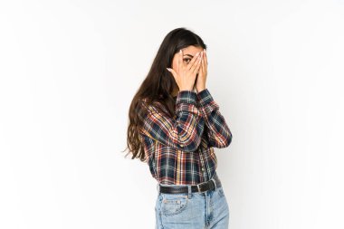 Mor arka planda izole edilmiş genç Hintli kadın parmaklarının arasından korkmuş ve gergin bir şekilde göz kırpıyor..