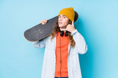 Kafkasyalı genç kaykaycı izole edilmiş, parmaklarıyla bir cep telefonu hareketi gösteriyor..