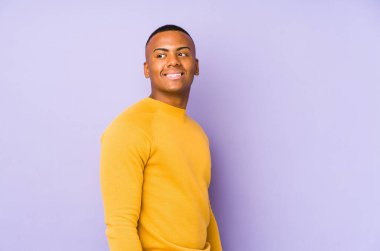 Mor arka planda soyutlanmış genç latin adam gülümseyen, neşeli ve hoş bakışları bir yana bırak..