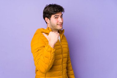 Mor arka plan noktalarında izole edilmiş genç bir adam başparmak uzakta, gülüyor ve kaygısız..