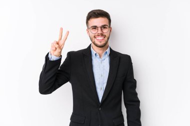 Beyaz arka planda poz veren beyaz tenli genç beyaz iş adamı zafer işareti gösteren ve gülümseyen Kafkasyalı genç bir iş adamı izole edildi..
