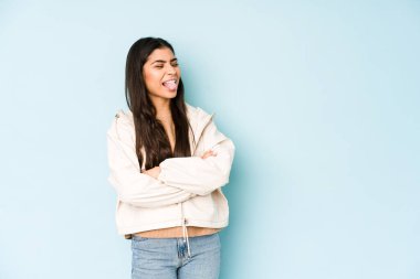 Mavi arka plandaki genç Hintli kadın. Komik ve dost canlısı. Dilini dışarı çıkarıyor..