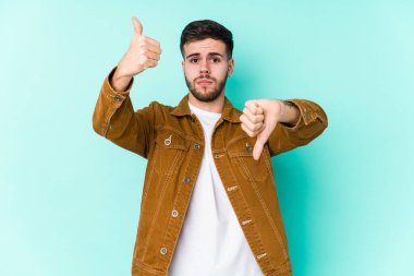 Genç yakışıklı adam baş parmağını kaldırıyor ve baş parmak aşağı, zor seçim konsepti