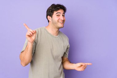 Mor arka planda izole edilmiş genç adam farklı kopya alanlarını gösteriyor, birini seçiyor, parmaklarıyla gösteriyor..