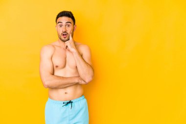 Sarı arka planda mayosu olan genç beyaz bir adam. Kafkasyalı genç ve harika bir fikri, yaratıcılığı olan bir adam..