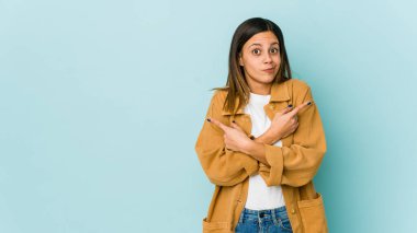 Mavi arka plan noktalarında izole edilmiş genç bir kadın iki seçenek arasında seçim yapmaya çalışıyor..