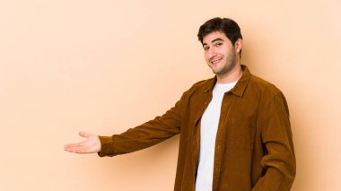 Bej arka planda izole edilmiş genç bir adam hoş bir ifade sergiliyor..