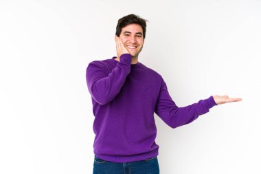 Beyaz arka planda izole edilmiş genç bir adam bir avuç içinde fotokopi alanı tutuyor, el üstünde tutuyor. Şaşırmış ve mutlu..