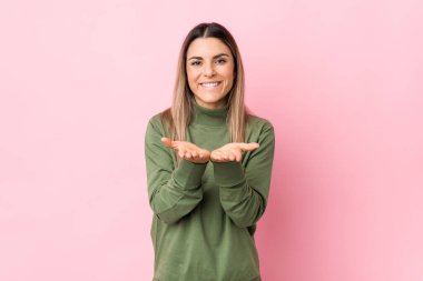 Kafkasyalı genç bir kadın avuçlarıyla bir şey tutarak kameraya sunuyor..