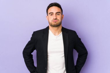 Mor arka planda izole edilmiş genç beyaz adam üzgün, ciddi yüz, sefil ve hoşnutsuz hissediyor.