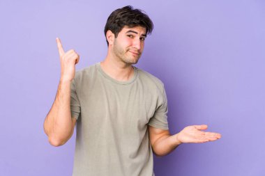 Mor arka planda izole edilmiş genç bir adam elinde bir ürün tutuyor..