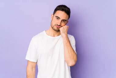 Mor arka planda izole edilmiş genç beyaz adam üzgün ve dalgın hissediyor, kopyalama alanına bakıyor..