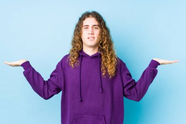 Yalnız poz veren uzun saçlı adam kollarıyla ölçek yapar, mutlu ve kendinden emin hisseder..