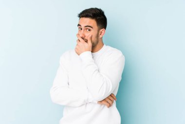 Kafkasyalı genç adam mavi arka planda izole edilmiş korkmuş ve korkmuş..