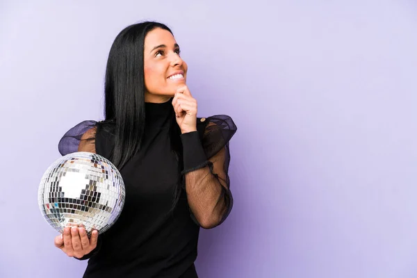 Woman Holding Ball Party Isolated Purple Background Looking Sideways Doubtful — Stock Photo, Image