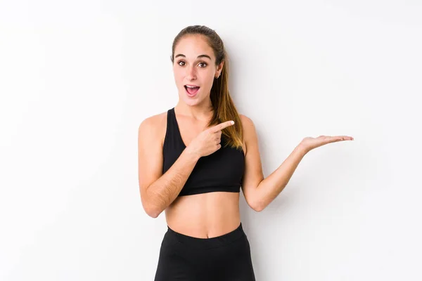 Joven Mujer Fitness Caucásica Posando Fondo Blanco Emocionado Sosteniendo Espacio —  Fotos de Stock