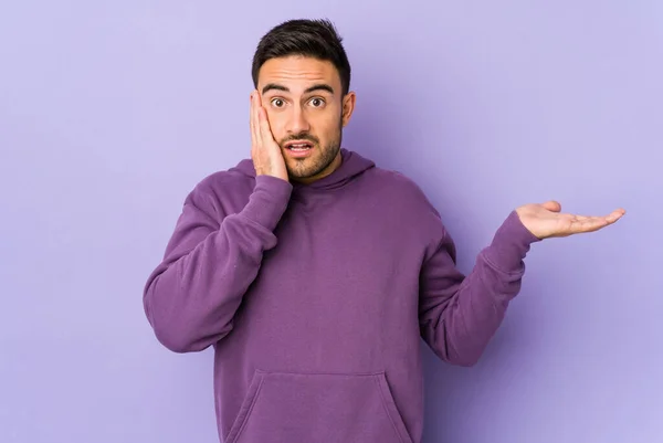 Jovem Caucasiano Isolado Fundo Roxo Impressionado Segurando Espaço Cópia Palma — Fotografia de Stock