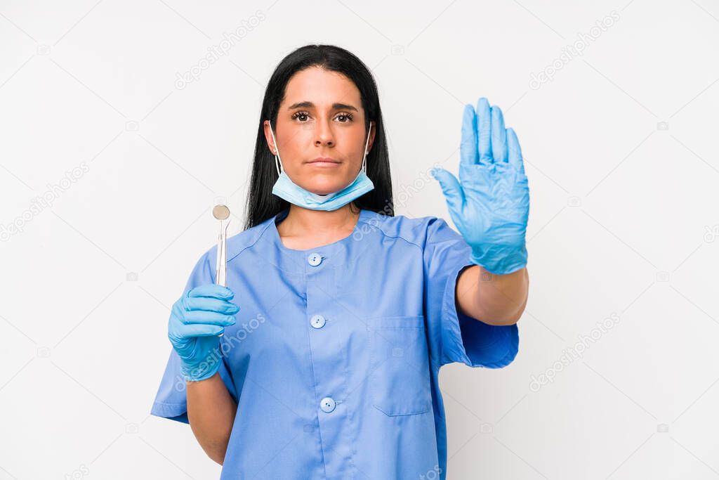 Dentist woman isolated on white background standing with outstretched hand showing stop sign, preventing you.