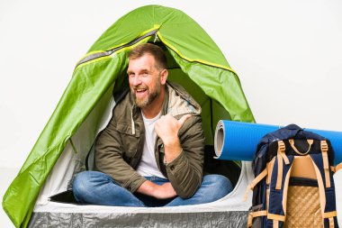 Beyaz arka plan noktalarında izole edilmiş bir çadırın içinde başparmak uzakta, gülen ve kaygısız.