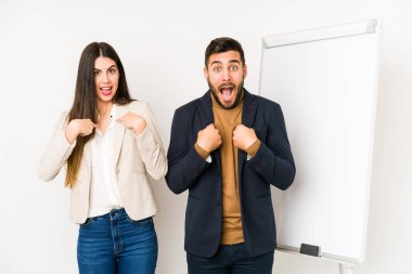 Kafkasyalı genç iş çifti izole edilmiş, şaşırmış, geniş bir gülümsemeyle işaret ediyor..