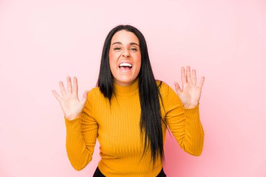 Pembe arka planda izole edilmiş genç beyaz kadın zaferi ya da başarıyı kutluyor, şaşırıyor ve şok oluyor..