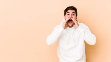 Bej arka planda izole edilmiş genç bir adam heyecanlı bir şekilde bağırıyor..