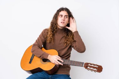 Gitar çalan beyaz bir adam bir dedikoduyu dinlemeye çalışıyor..