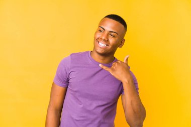 Sarı arka planda izole edilmiş genç latin adam parmakları olan bir cep telefonu hareketi gösteriyor..