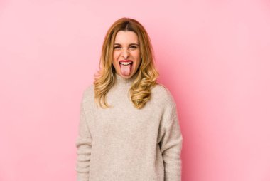 Süveter giyen genç sarışın hoş bir kadın. Tuhaf ve arkadaş canlısı bir dil uzatıyor..