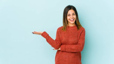 Mavi arka planda izole edilmiş genç bir kadın bir avuç içinde fotokopi alanı ve belinde bir el daha olduğunu gösteriyor..