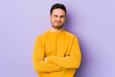 Mor arka planda izole edilmiş genç beyaz adam alaycı bir ifadeyle kameraya bakarken mutsuz oluyor..