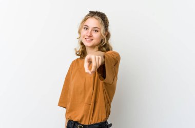 Beyaz arka plandaki genç beyaz kadın parmaklarıyla ön tarafı işaret ediyor..