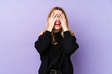 Sarışın genç bir kadın izole edilmiş. Elleriyle gözlerini kapatıyor. Gülümsüyor ve bir sürpriz bekliyor..